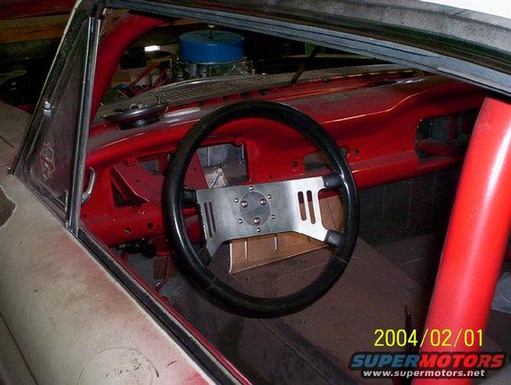 1963 Ford Falcon interior showing racing steering wheel, red roll cage, and dashboard