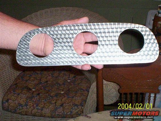 Hand holding a brushed aluminum gauge cluster bezel with three circular cutouts