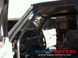Interior of a truck, doors open, steering wheel visible. Looks like it's being worked on