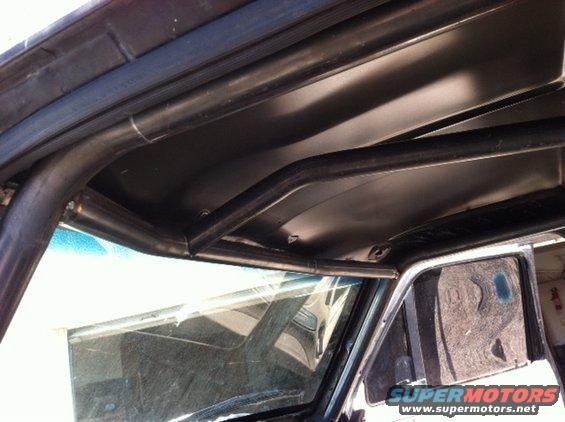 Interior view of a vehicle with a custom roll cage installed around the roof and windshield area