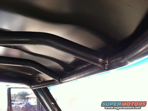 Interior view of a vehicle's roll cage, showing metal tubing welded together under the headliner