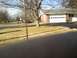 1995 Mercury Grand Marquis - A dark sedan is parked on the side of a street in front of a house with a white garage door.