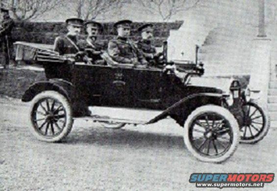 Dark touring car with four men in uniform, seen from the front-right