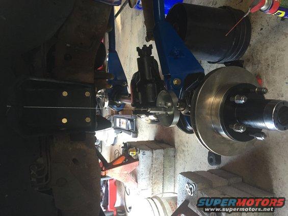 Close-up of a vehicle's rear axle assembly with a new brake rotor and hub, undergoing maintenance