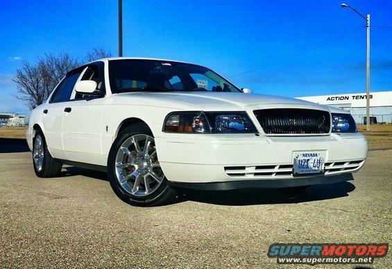 White 2000 Mercury Grand Marquis with aftermarket wheels parked on gravel
