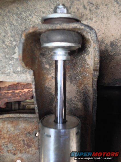 Close-up of a vehicle's shock absorber mounting bracket with a rubber bushing and bolt