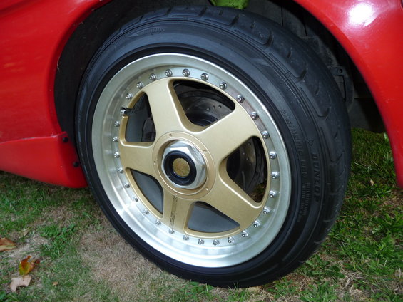 Gold five-spoke wheel and Dunlop tire on red car
