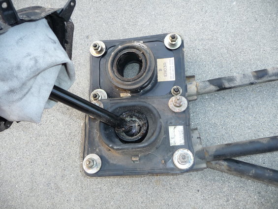 Car gear shifter assembly with rubber boots and metal rods, one rod covered by a cloth