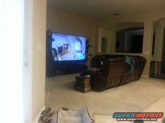 Living room scene with large TV displaying a room and a brown recliner