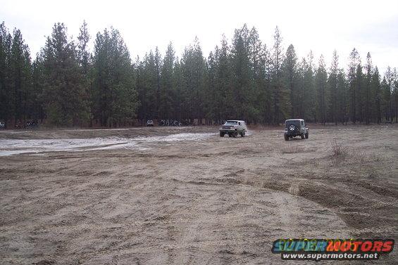 Two SUVs driving on a dirt field