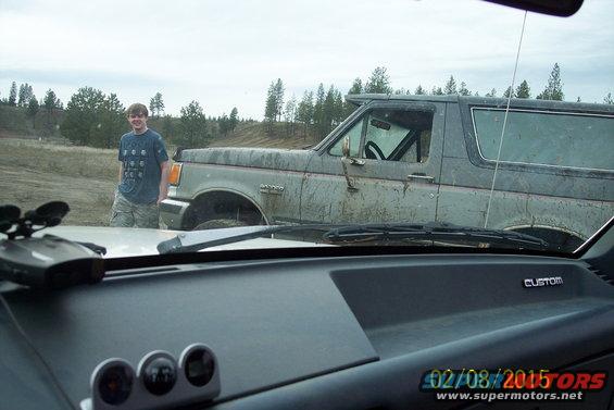 1990 Ford Bronco parked in a field with a person standing next to it