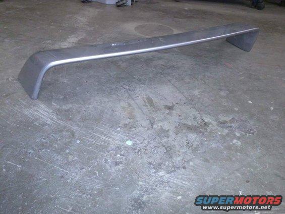 Gray rear spoiler with silver trim, resting on a concrete floor