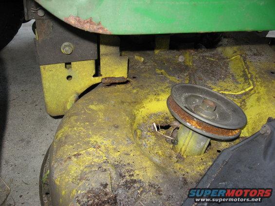 Close-up of a rusty lawn mower deck with a pulley and belt