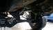 1988 Ford Bronco - Focus on the undercarriage components, including the leaf springs and driveshaft, with another vehicle partially visible.