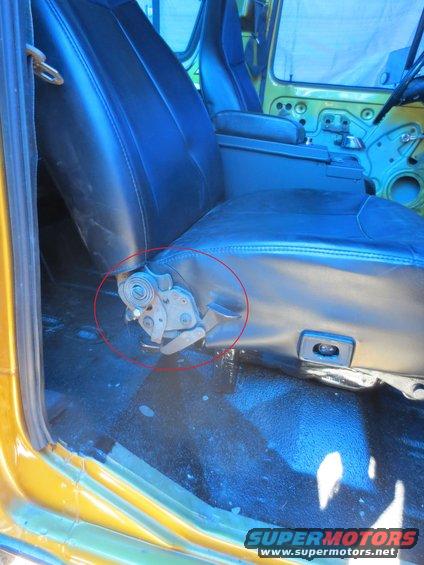 Vehicle interior with black vinyl seats and yellow exterior paint. Seat adjustment mechanism circled in red