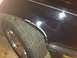 1988 BMW 7 Series - Close-up of damaged black car fender showing scraped paint and rust around the wheel well.