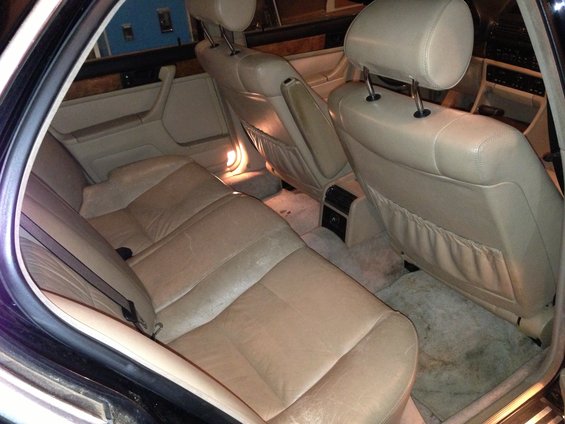 Back seats and interior of a car. Beige leather seats and door panels are visible