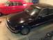 1988 BMW 7 Series - A black 1988 BMW 7 Series sedan is parked next to a red classic car.