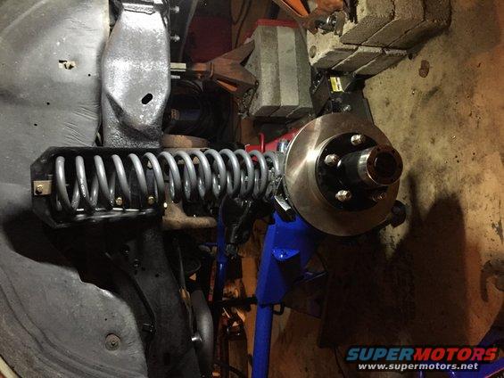 close-up of a vehicle's front suspension with a coil spring and brake rotor