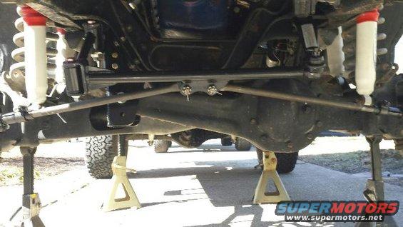 Undercarriage of a vehicle on jack stands, showing suspension and differential