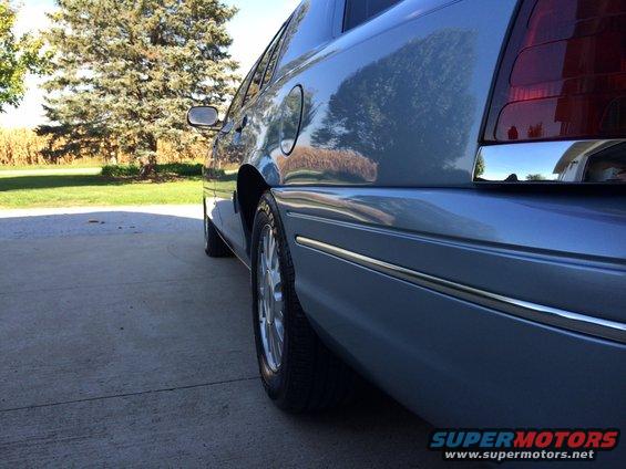Light blue sedan rear quarter panel with chrome trim and taillight visible. 2003 Ford Crown Victoria