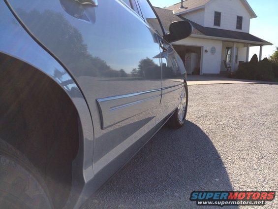 car's side panel and rear wheel, parked in front of a house