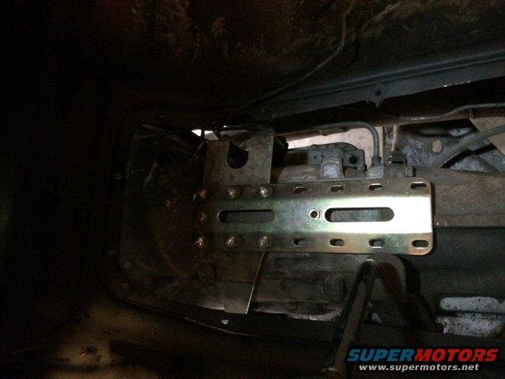 Close-up of a vehicle's transmission with a metal mounting bracket attached