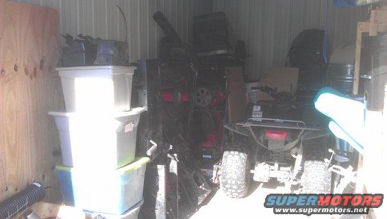 Black all-terrain vehicle, rear view, parked in storage unit with plastic bins