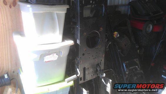 Black metal frame of a lawn mower with two stacked storage bins to the left