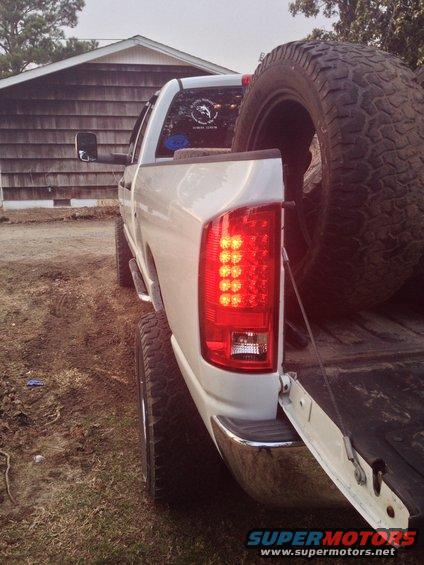 White pickup truck rear view with LED tail lights and spare tire in bed