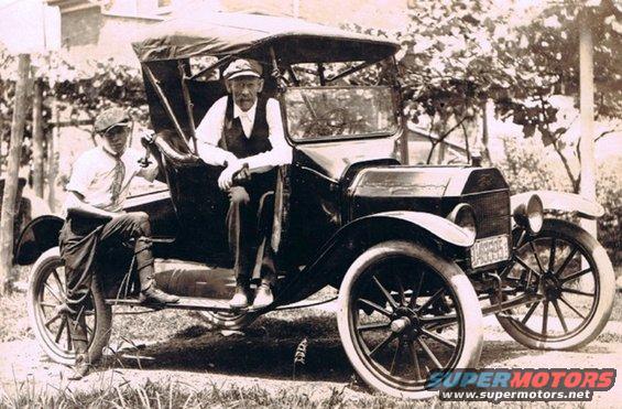 1915 Ford Model T with two men, one standing by the door, the other seated inside