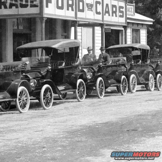 Several 1915 Ford Model Ts parked in a row outside a Ford dealership