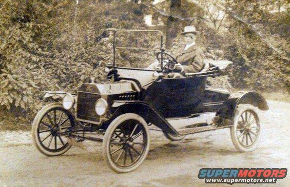 1915 Ford Model T runabout with a person driving, seen from the front three-quarter view