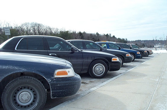 Side view of a line of dark 1991 Ford Crown Victoria LTD sedans parked in a lot