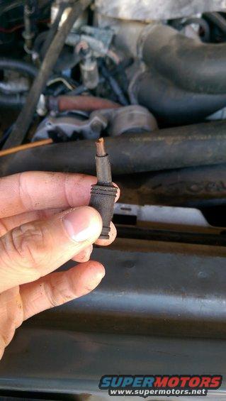 Hand holding a small black vacuum line fitting with a copper tip