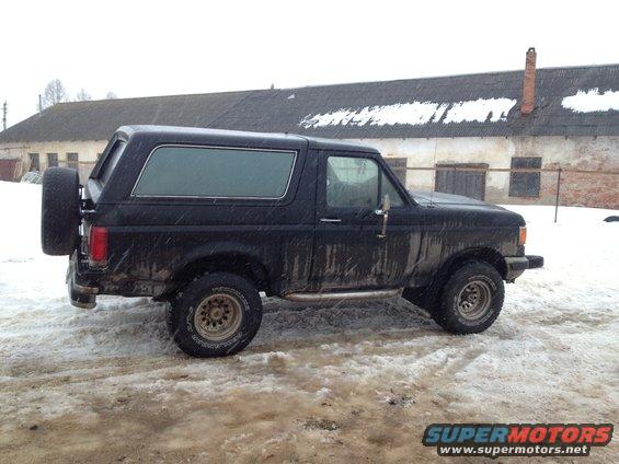 1987 Ford Bronco parked in snow, side view with spare tire on rear door