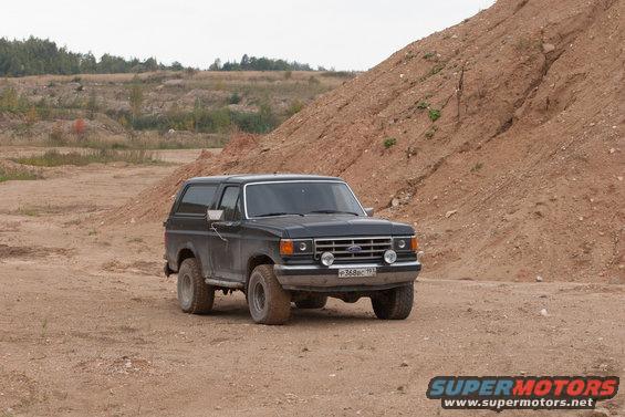 Black Ford Bronco parked on dirt road near a sandy hill
