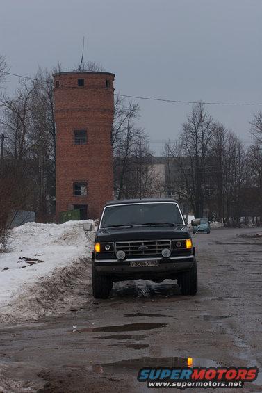 Black 1987 Ford Bronco front view, driving on a wet road with snow on the side