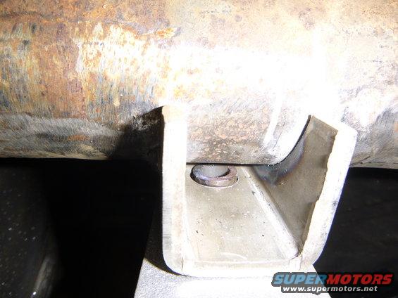 Close-up of a rusty metal pipe with a U-shaped bracket attached