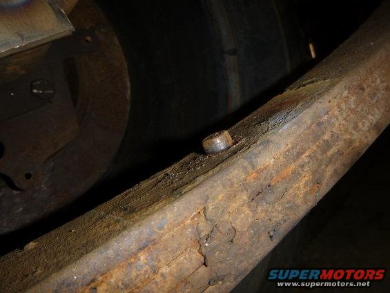 Close-up of a rusty metal beam with a bolt, part of a vehicle's frame