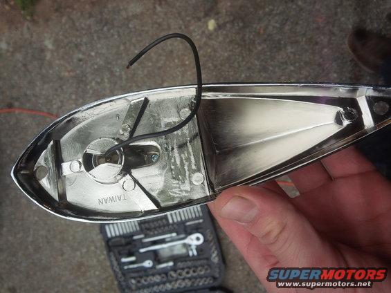 Chrome trim piece with wiring, marked 'TAIWAN', held over a toolbox