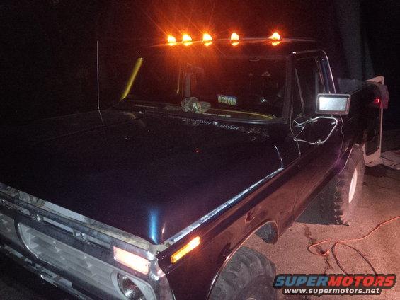 1978 Ford Bronco with amber roof marker lights, dark blue paint, and chrome grille