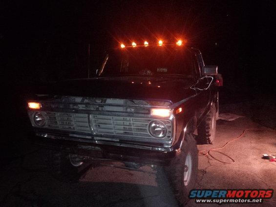 Front view of a dark Ford F-Series truck at night with cab lights on. Grille and headlights visible