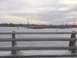 1979 Ford Bronco - A frozen body of water stretches to the horizon under a cloudy sky, viewed from behind a metal bridge railing.