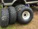 1971 Ford F-250 - Four aggressive off-road tires are displayed next to a single polished aluminum wheel, with the lower body of a vehicle visible in the back…