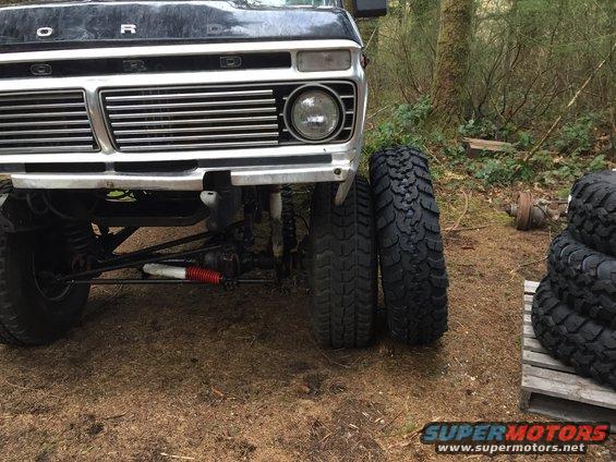 Black 1973 Ford F-Series truck front end with chrome grille and large off-road tires