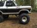 1971 Ford F-250 - This lifted SUV features a two-tone black and silver paint scheme with prominent off-road tires, suggesting a model from the late 1970s.