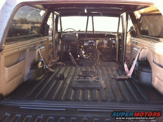 Interior of a vehicle with seats removed, roll cage installed, and dashboard wiring exposed