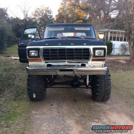 Front view of a lifted black Ford F-Series truck with its driver's door open. It has a chrome bumper and grille