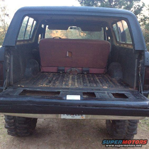 Rear view of a dark blue 1978 Ford Bronco with a maroon bench seat and a dirty cargo bed